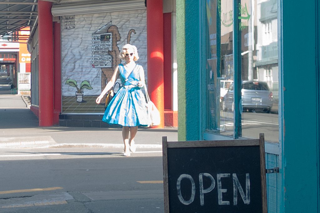 Woman in blue dress crossing road in Cuba Street