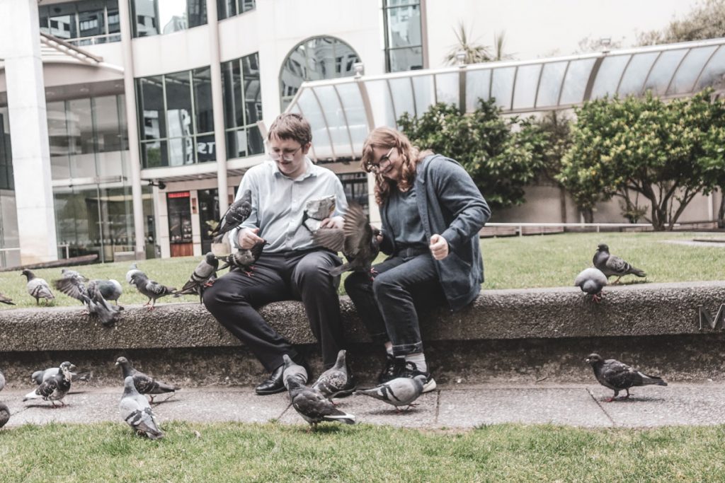 Couple sitting with pigeons in Lambton Quay