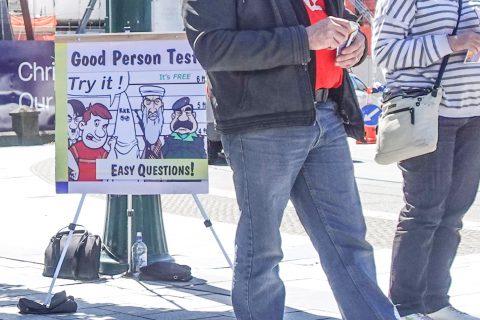 Two people standing in front Good Person Test sign