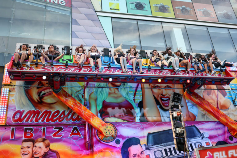 People on a brightly lit amusement ride, symbolising the speed and sensory overload of modern life
